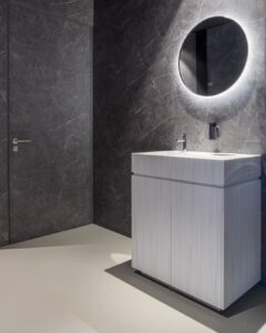 Toilet in de showroom van DecoLegno waarbij de muren zijn uitgevoerd in de FC19 Talco van Cleaf, een donkergrijze marmerlook met ultra matte finish, en het wastafelmeubel in de DM5015 Luna van Durasein, met een vloeiend lijnenspel in een serene, witte kleurmelange.