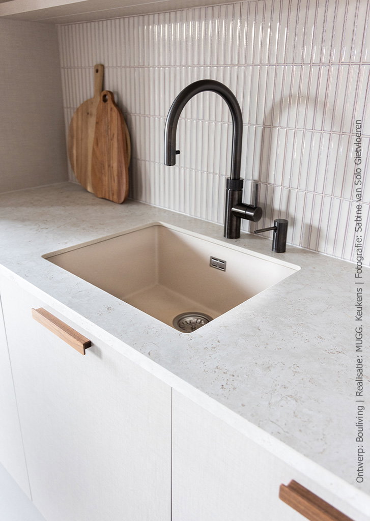 Closeup beeld van een keuken uitgevoerd in decoratief plaatmateriaal met linnenstructuur in FA44 Penelope in lichtbeige met op de achterwand langwerpige beige tegels