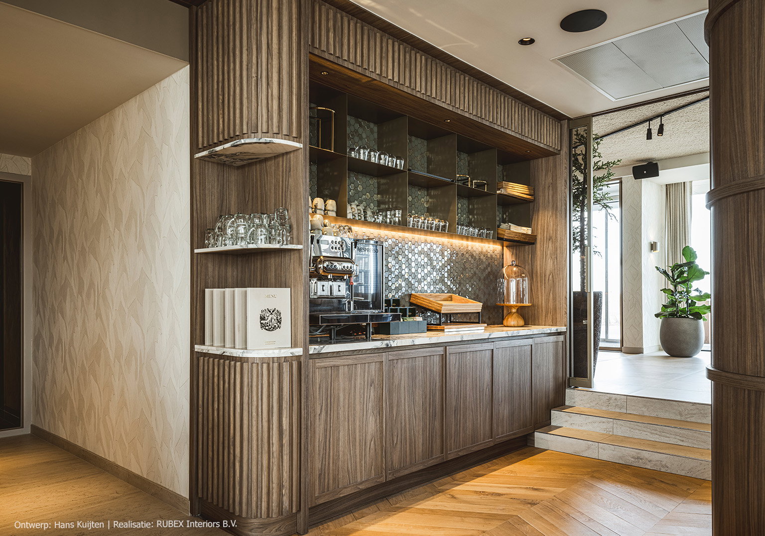 Maatwerk pantry in hotel, uitgevoerd in LS13 Poro Noce, een warm lichtbruin walnootdecor met levendige nerftekening.