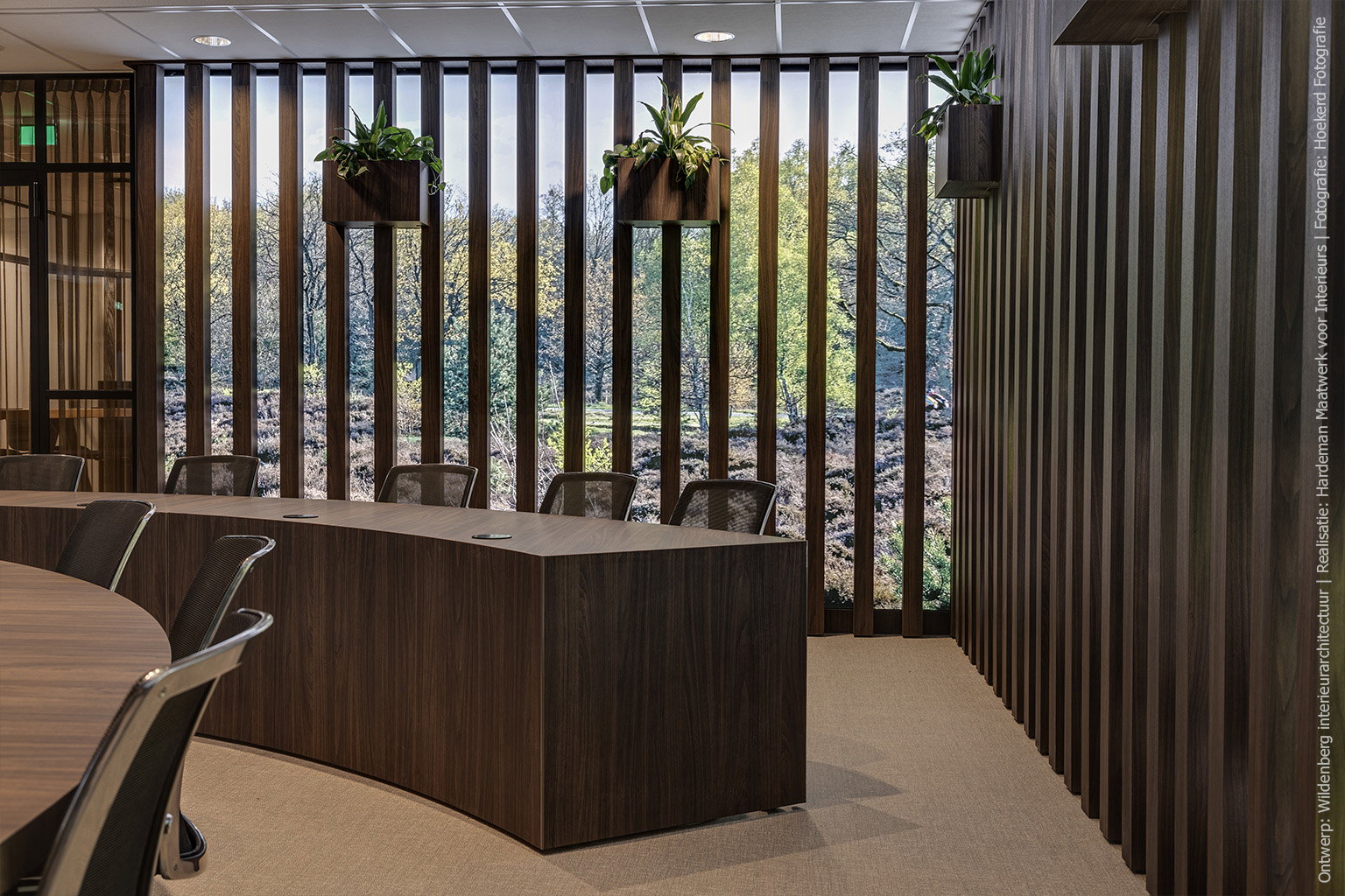 Raadszaal met grote vergadertafel in Cleaf LS17 Poro Noce, groene zitbanken en verticale raamdecoratie.