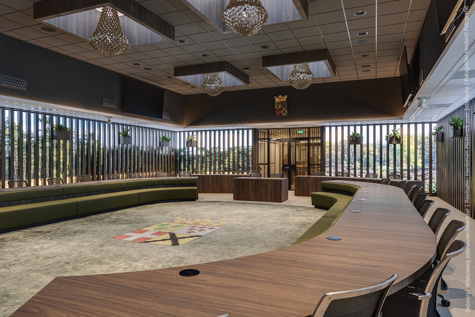 Raadszaal met grote vergadertafel in Cleaf LS17 Poro Noce, groene zitbanken en verticale raamdecoratie.