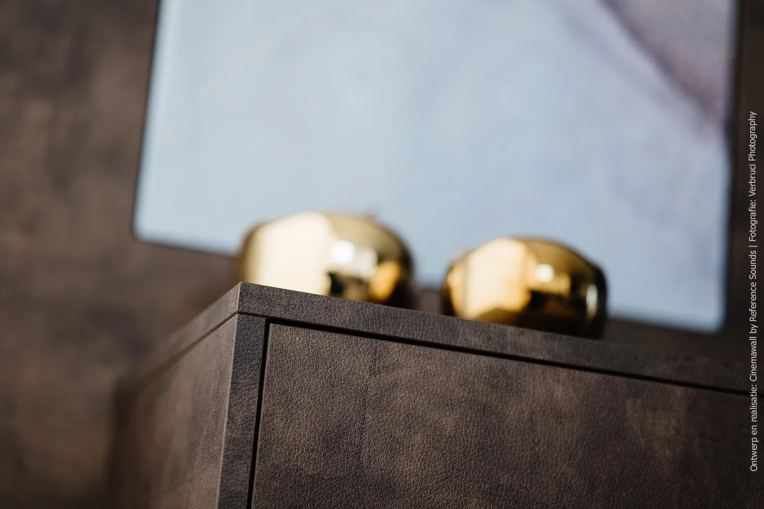 Close-up van het kastfront in decor FA33 Primofiore met voelbare leerstructuur en gouden decoratieve accessoires op de voorgrond.